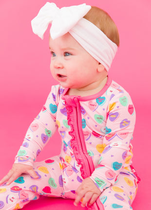 Model Wearing Rufflebutts + Ruggedbutts Baby Girls Be My Valentine Bamboo Viscose Footed Ruffle One Piece Pajama