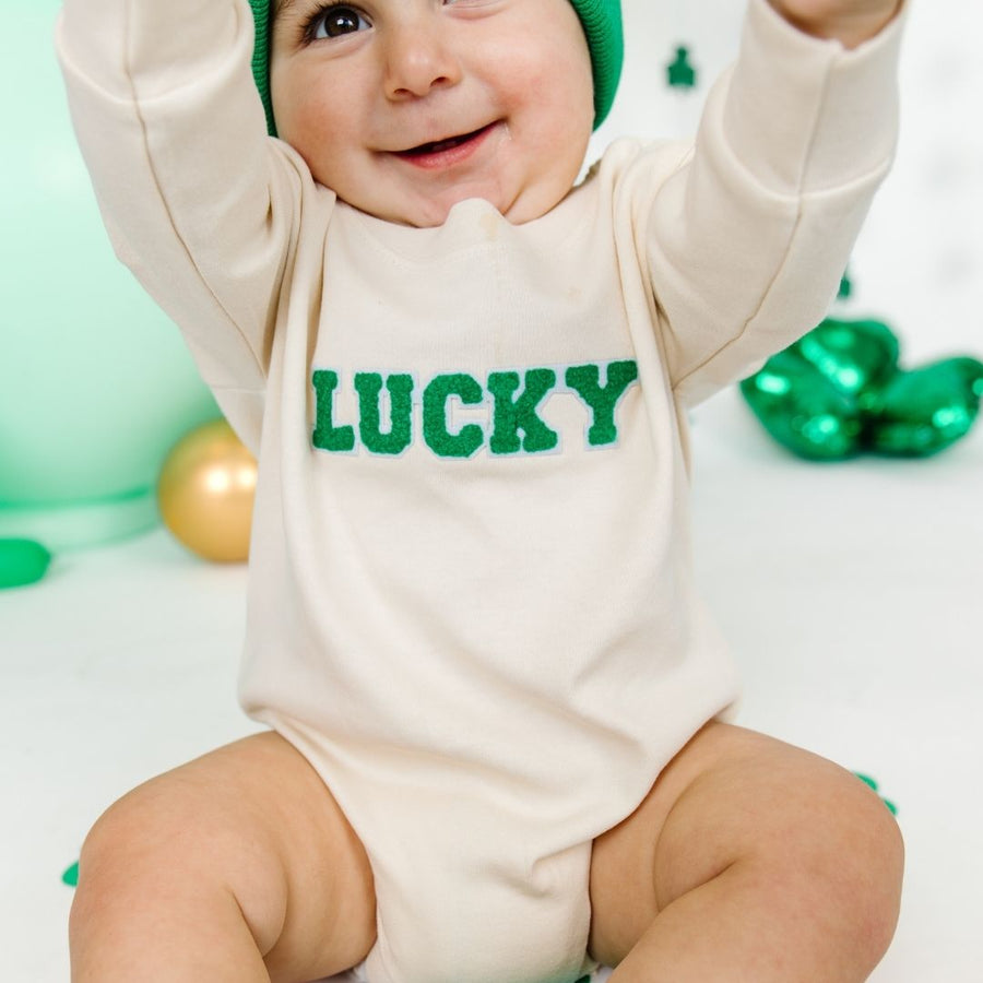 Model wearing Lucky Varsity Patch St. Patrick's Day Long Sleeve Romper - Natural