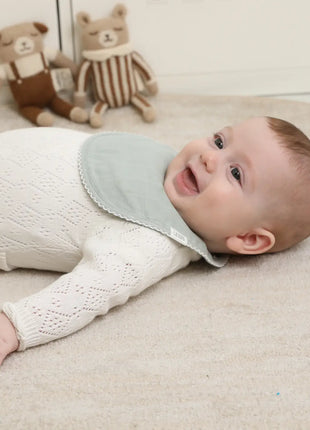 Baby wearing a Sage Muslin teething bib Adora baby