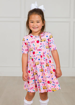 Model Wearing Rufflebutts + Ruggedbutts Girls Pink School House Short Sleeve Knit Twirl Dress