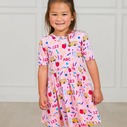 Model Wearing Rufflebutts + Ruggedbutts Girls Pink School House Short Sleeve Knit Twirl Dress