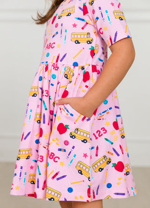 Model Wearing Rufflebutts + Ruggedbutts Girls Pink School House Short Sleeve Knit Twirl Dress