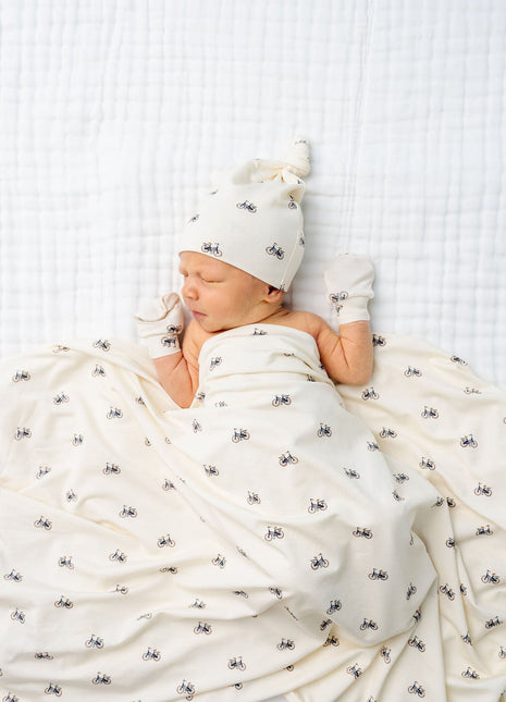 Model Wearing Lou Lou & Company Freddy Top Knot Hat, Swaddle, and Mittens