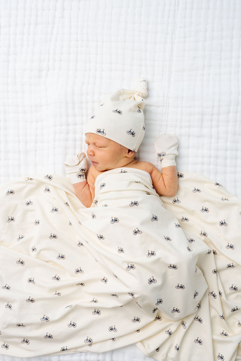 Model Wearing Lou Lou & Company Freddy Top Knot Hat, Swaddle, and Mittens