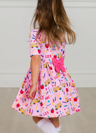 Model Wearing Rufflebutts + Ruggedbutts Girls Pink School House Short Sleeve Knit Twirl Dress