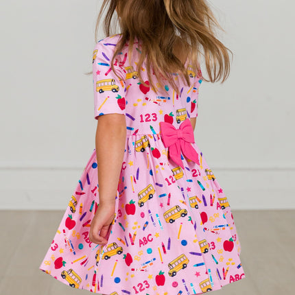 Model Wearing Rufflebutts + Ruggedbutts Girls Pink School House Short Sleeve Knit Twirl Dress