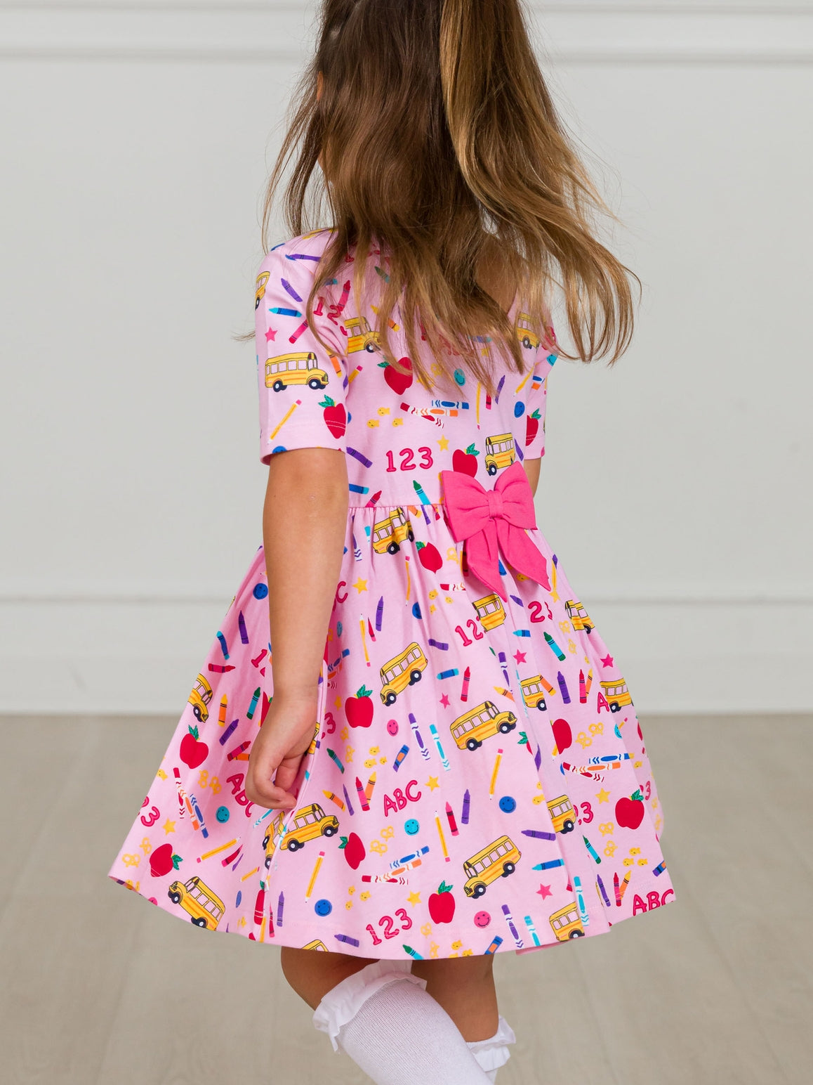 Model Wearing Rufflebutts + Ruggedbutts Girls Pink School House Short Sleeve Knit Twirl Dress