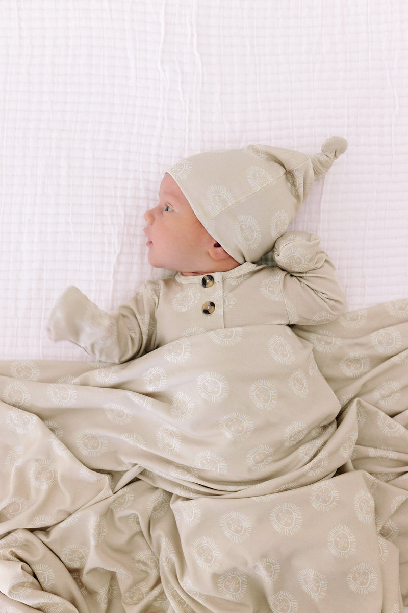 Model Wearing Lou Lou & Company Linus Top Knot Hat, knotted gown, and swaddle